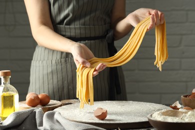 Photo of Woman making homemade pasta at table, closeup