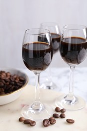 Photo of Glasses of coffee liqueur and beans on white table