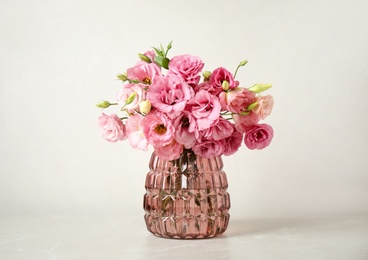 Beautiful pink Eustoma flowers in vase on light background