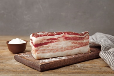 Board with bacon and salt on wooden table. Space for text