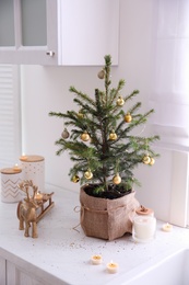 Small decorated Christmas tree and reindeer figure on countertop in kitchen