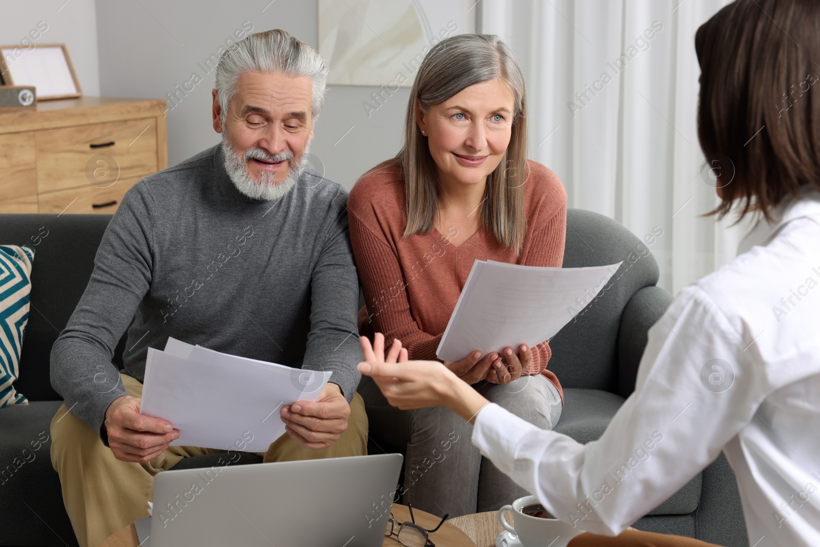 Photo of Insurance agent consulting elderly couple about pension plan in room