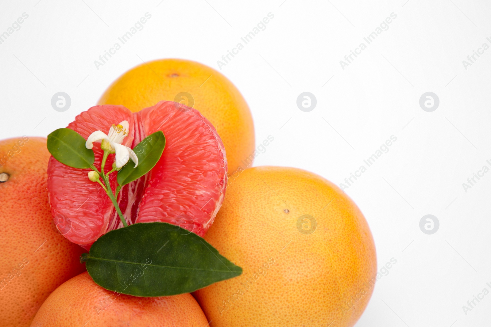 Photo of Fresh grapefruits and green leaves on white background, closeup. Space for text