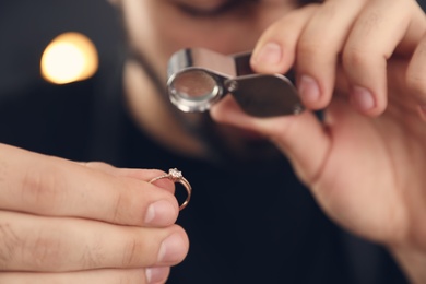 Photo of Male jeweler evaluating ring in workshop, closeup