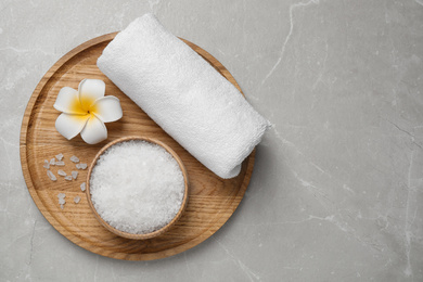 Sea salt, towel and flower on grey marble table, top view with space for text. Spa treatment