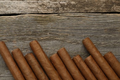 Many cigars on wooden table, flat lay. Space for text