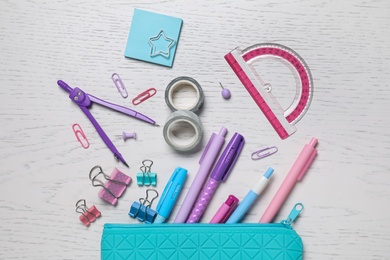 Different school stationery and pencil case on white wooden table, flat lay