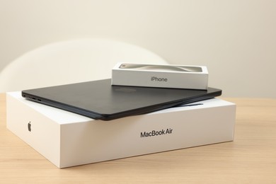 Photo of Leiden, Netherlands - October 6, 2023: Modern black MacBook Air and box from iPhone 15 Pro Max on wooden table