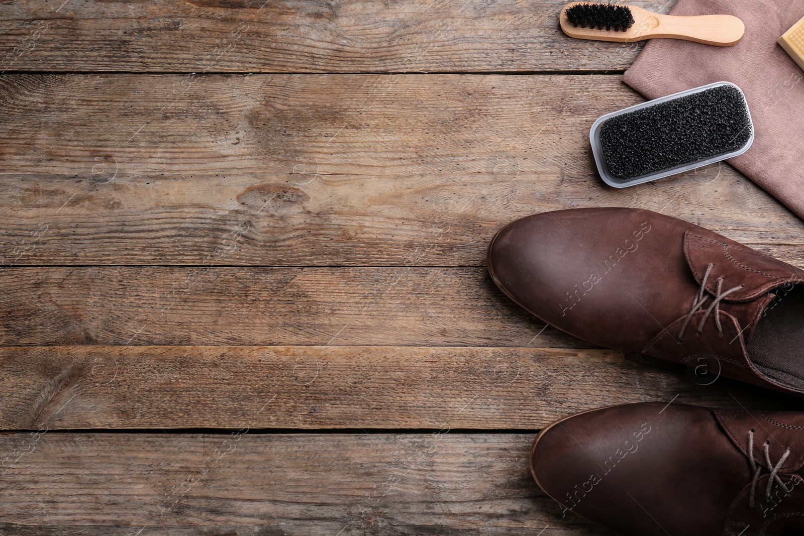 Photo of Stylish footwear with shoe care accessories on wooden table, flat lay. Space for text