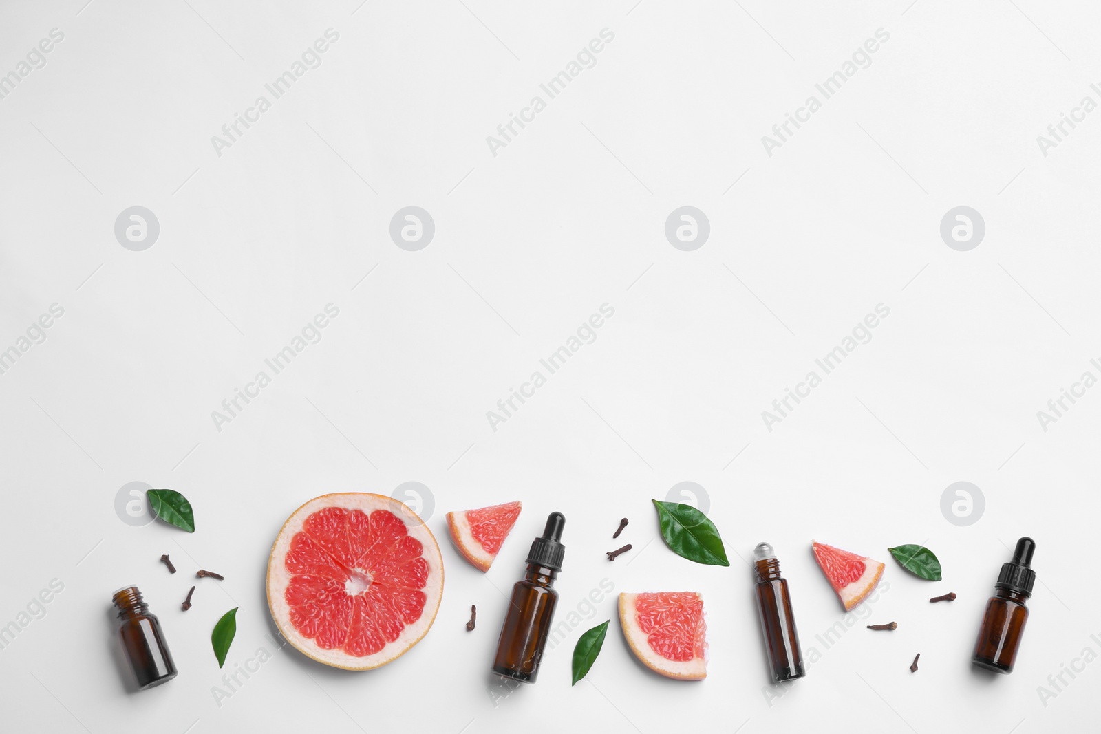 Photo of Composition with grapefruit slices and bottles of essential oil on white background, top view