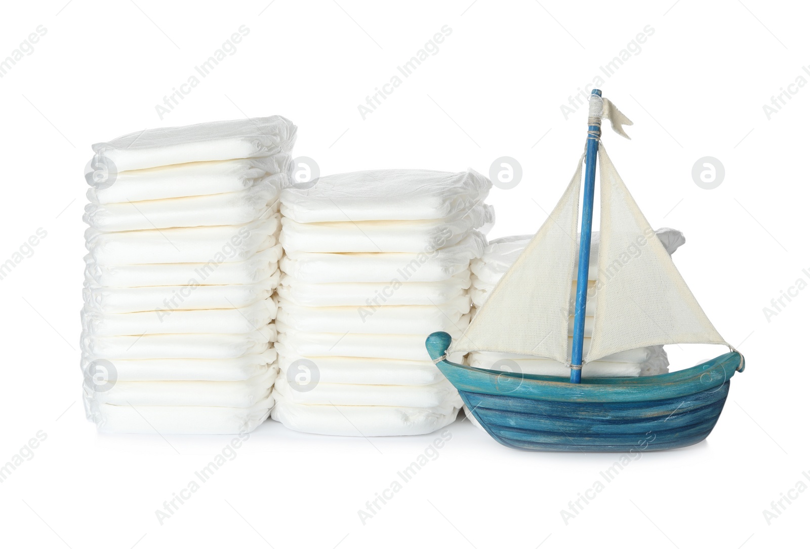 Photo of Disposable diapers and toy sailboat on white background