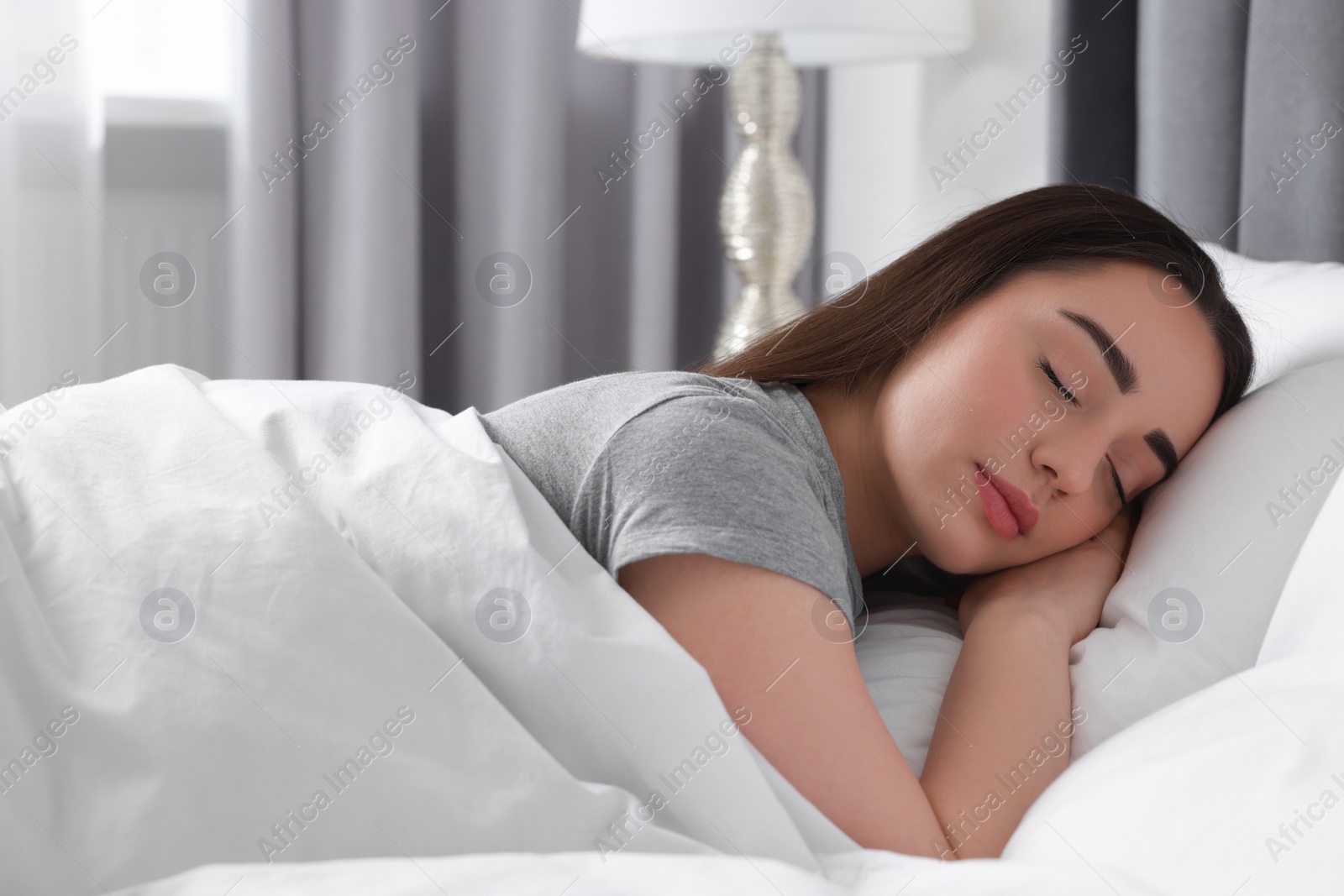 Photo of Beautiful young woman sleeping in soft bed at home