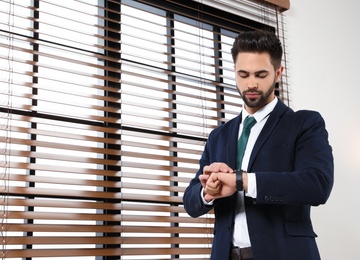 Photo of Portrait of confident businessman checking time at window indoors. Space for text