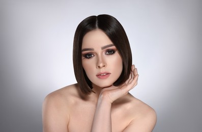 Image of Portrait of pretty young woman with brown hair on grey background