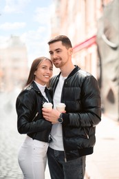 Photo of Lovely young couple with cups of coffee together on city street. Romantic date