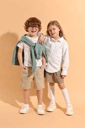 Photo of Fashion concept. Stylish children on pale orange background