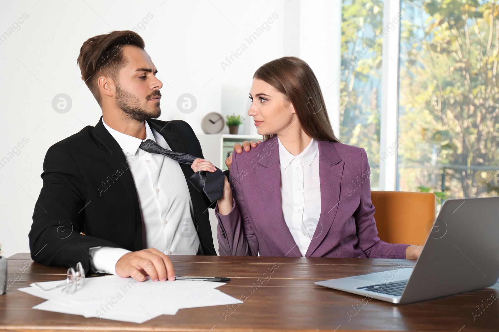 Photo of Woman molesting her male colleague in office. Sexual harassment at work