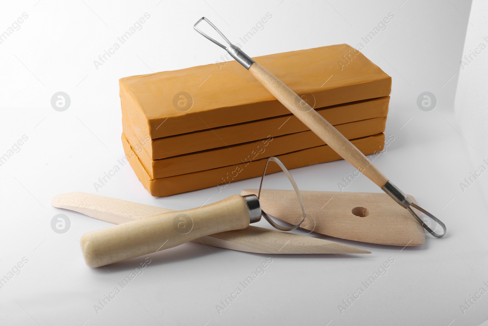 Photo of Clay and different modeling tools on white background