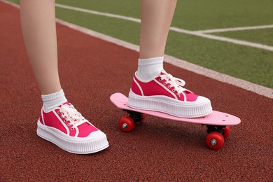 Photo of Woman with penny board wearing classic old school sneakers on sport court outdoors, closeup