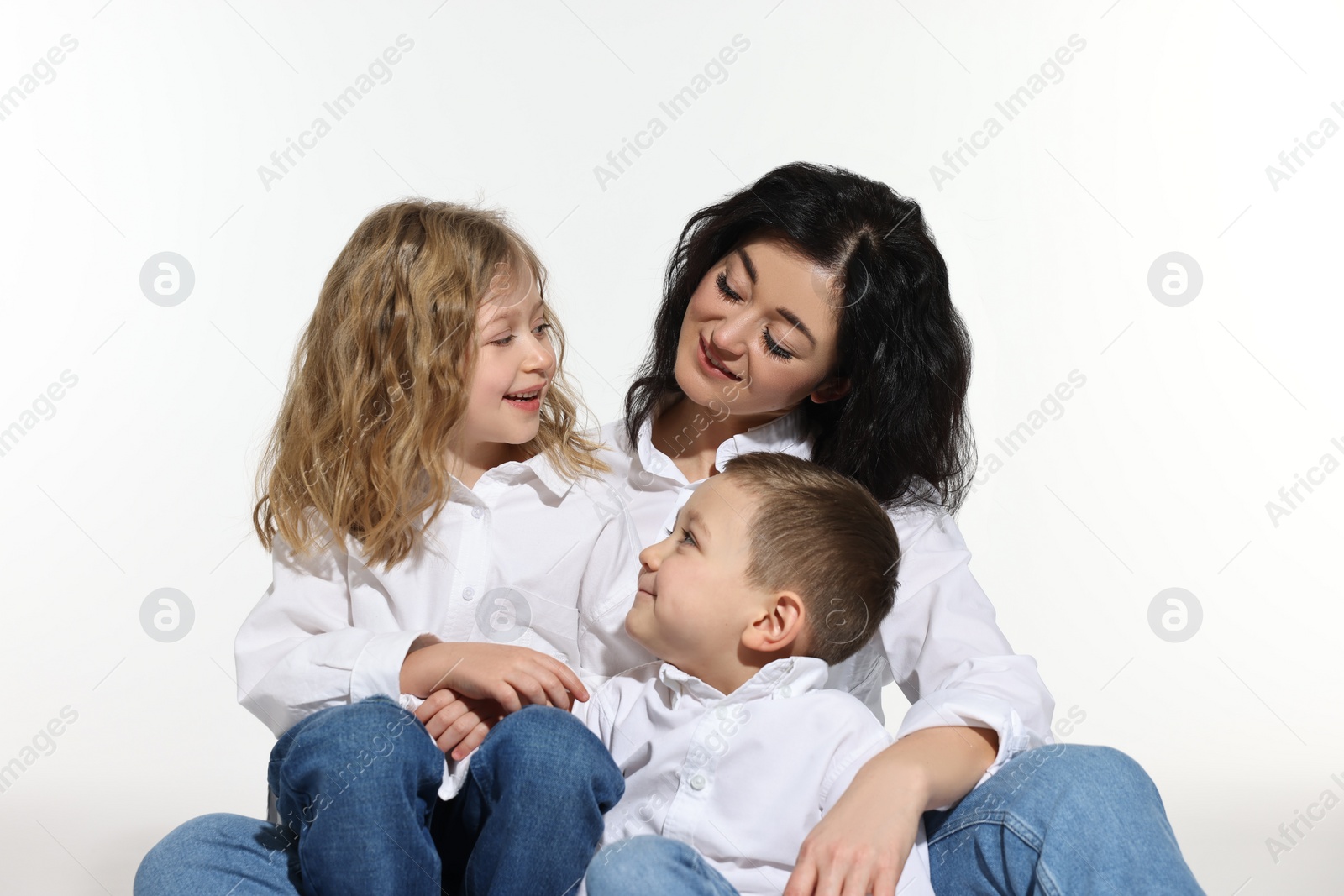 Photo of Little children with their mother sitting together on white background