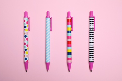 Photo of Stylish retractable pens on pink background, flat lay