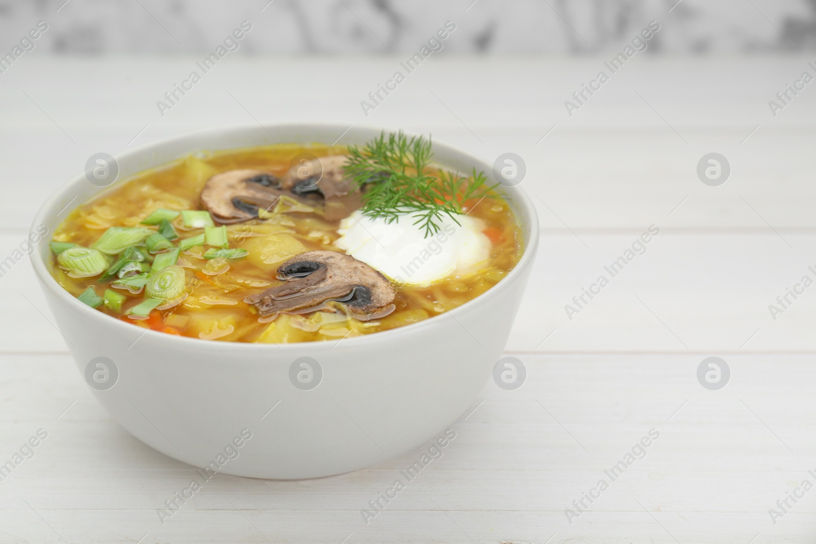 Photo of Delicious sauerkraut soup with mushrooms, green onion, dill and sour cream on white table. Space for text