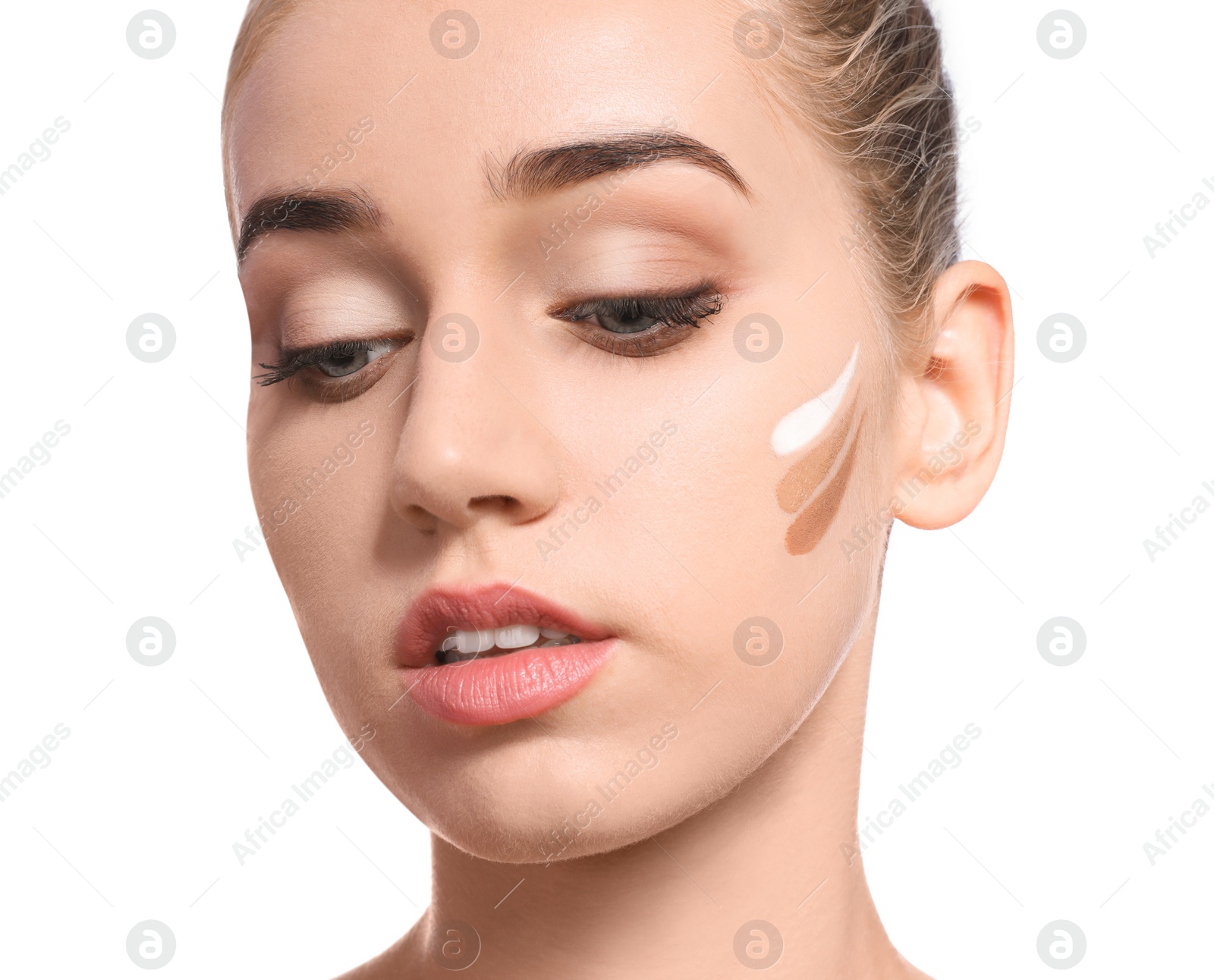 Photo of Young woman with different shades of skin foundation on her face against white background. Professional makeup