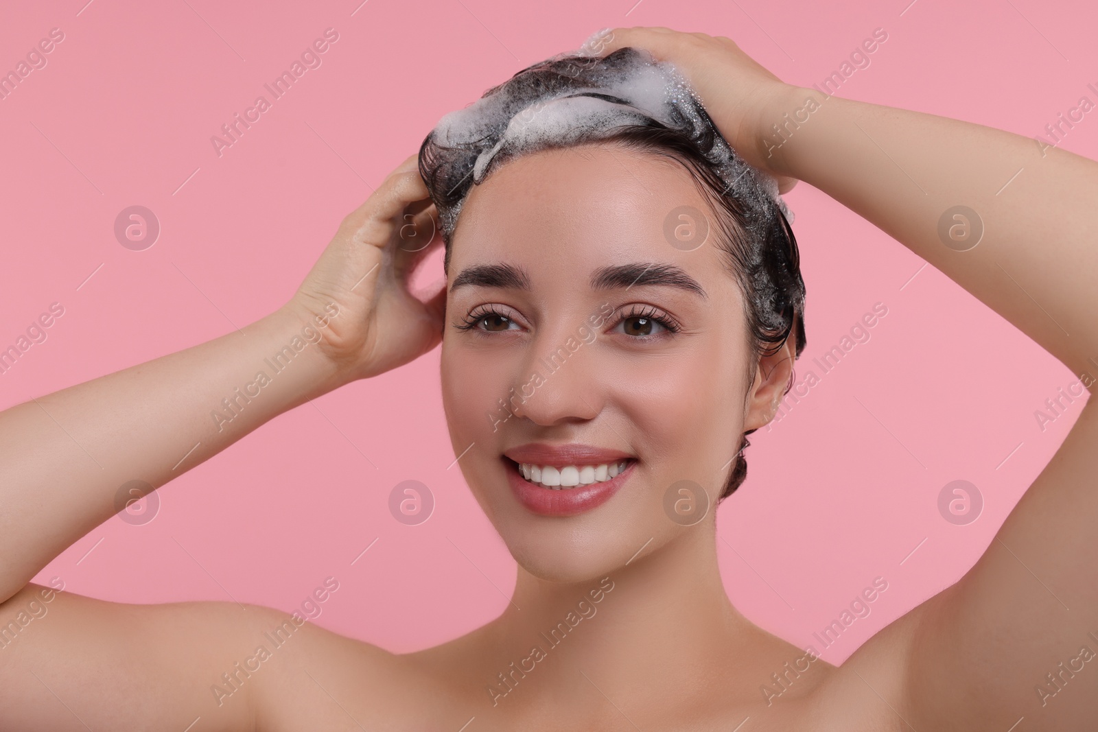 Photo of Portrait of beautiful happy woman washing hair on pink background