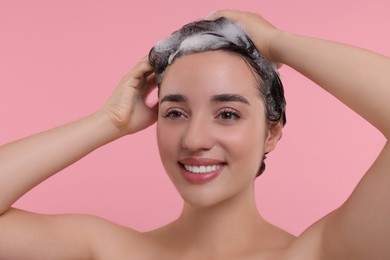 Portrait of beautiful happy woman washing hair on pink background