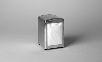 Photo of Napkin holder with paper serviettes on gray background