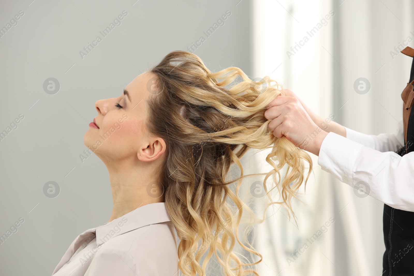 Photo of Hair styling. Professional hairdresser working with client indoors, closeup