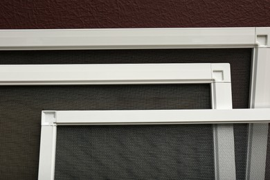 Photo of Set of window screens near brown wall, closeup