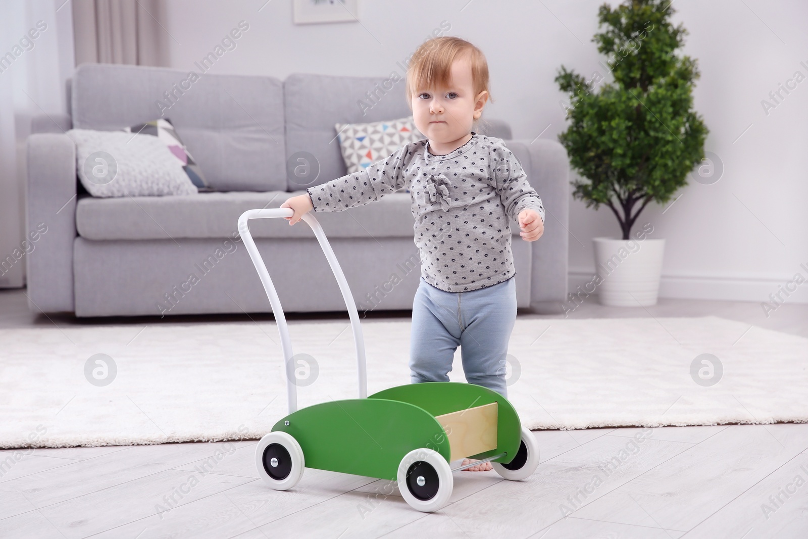 Photo of Cute baby playing with toy walker at home