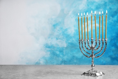 Photo of Hanukkah menorah on table against color background