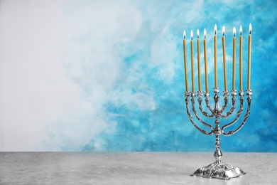 Hanukkah menorah on table against color background