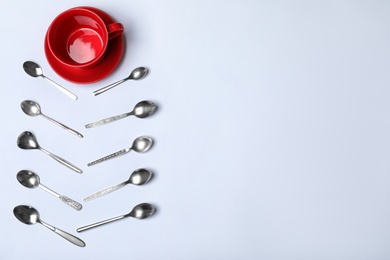 Photo of Composition with new metal spoons and red cup on white background, top view