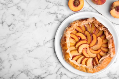 Delicious fresh peach pie on white marble table, flat lay. Space for text