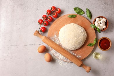 Pizza dough, products and rolling pin on gray textured table, flat lay. Space for text