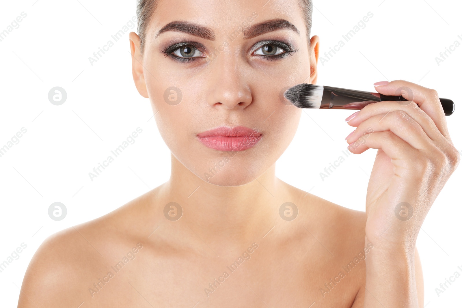 Photo of Portrait of beautiful woman applying stylish makeup with brush on white background