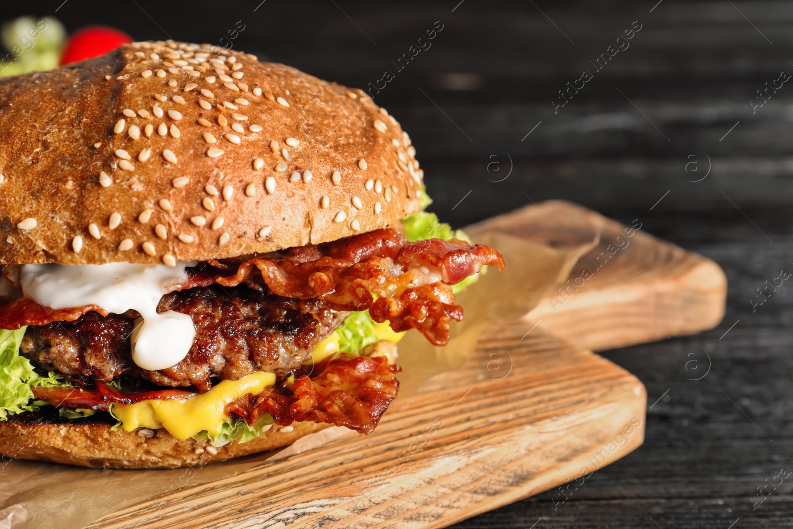 Photo of Tasty burger with bacon on wooden board