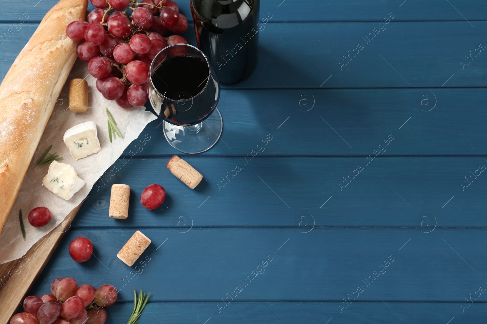 Photo of Flat lay composition with red wine and snacks on blue wooden table, space for text