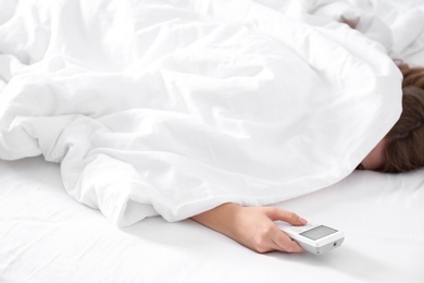 Woman holding air conditioner remote control in bed, focus on hand