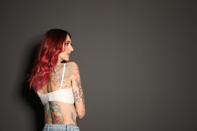 Beautiful woman with tattoos on body against black background. Space for text