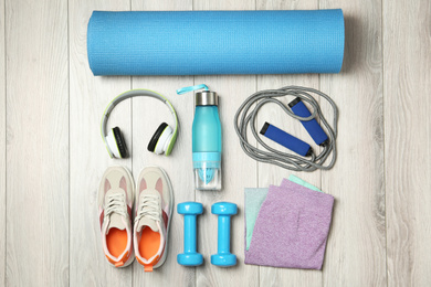 Set of fitness equipment and accessories on wooden background, flat lay