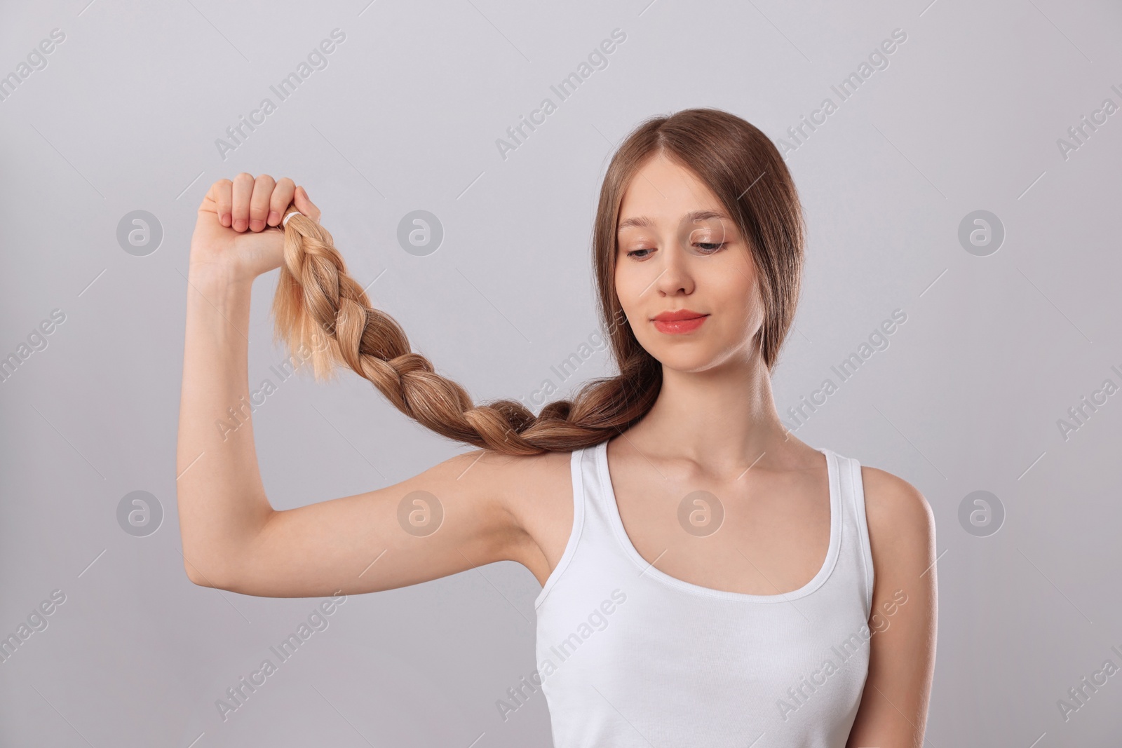 Photo of Teenage girl with strong healthy braided hair on light grey background