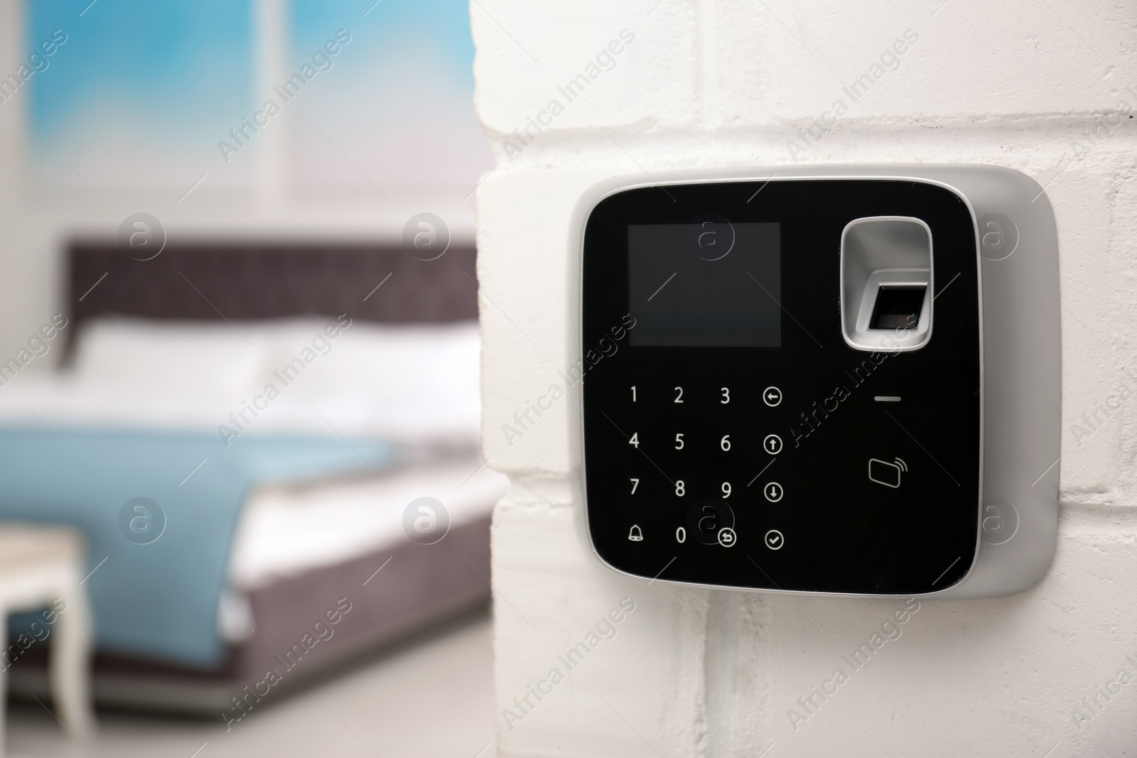 Photo of Modern alarm system with fingerprint scanner on brick wall in house. Space for text