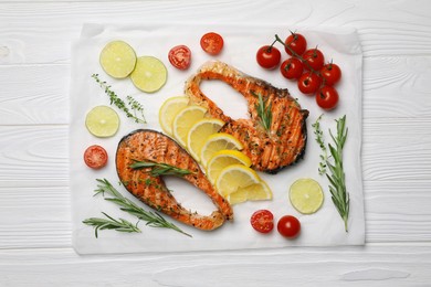 Tasty grilled salmon steaks and ingredients on white wooden table, top view