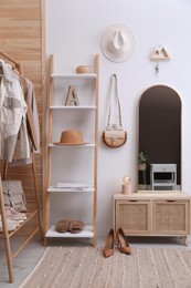 Modern hallway interior with stylish furniture and wooden hanger for keys on white wall