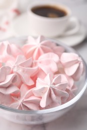 Tasty meringue cookies in bowl on white marble table, closeup