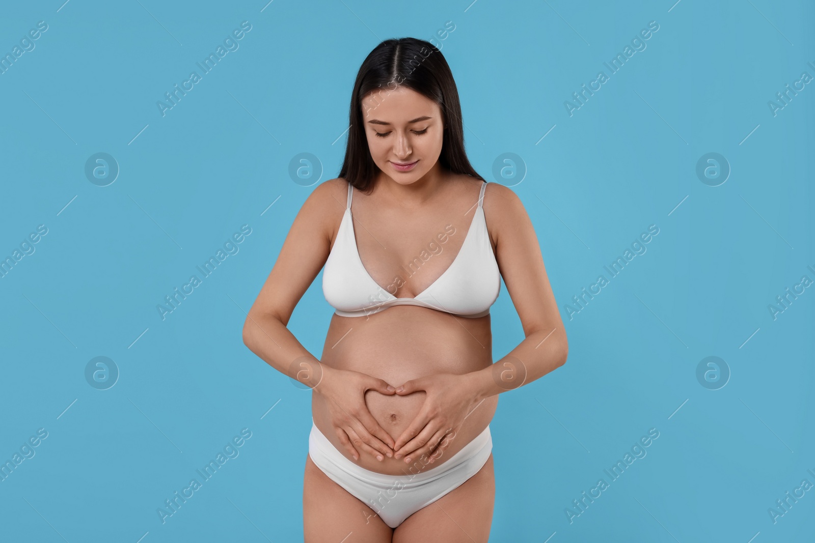 Photo of Beautiful pregnant woman in stylish comfortable underwear on light blue background